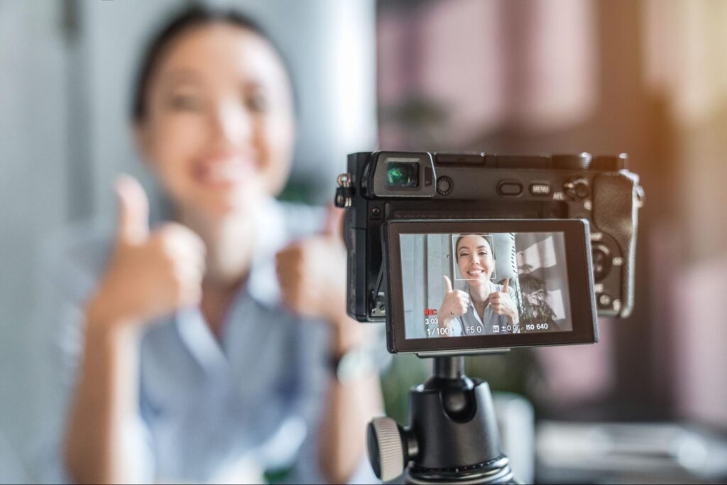 Close up photo of digital camera with young female influencer